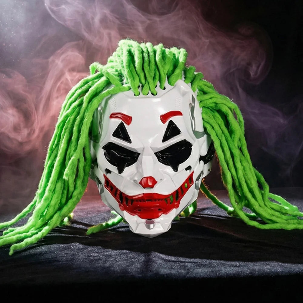 A Joker-style clown mask with bright green dreadlock-like hair, shown against a dark smoky background. The mask is white with red and black painted facial details and red lips.